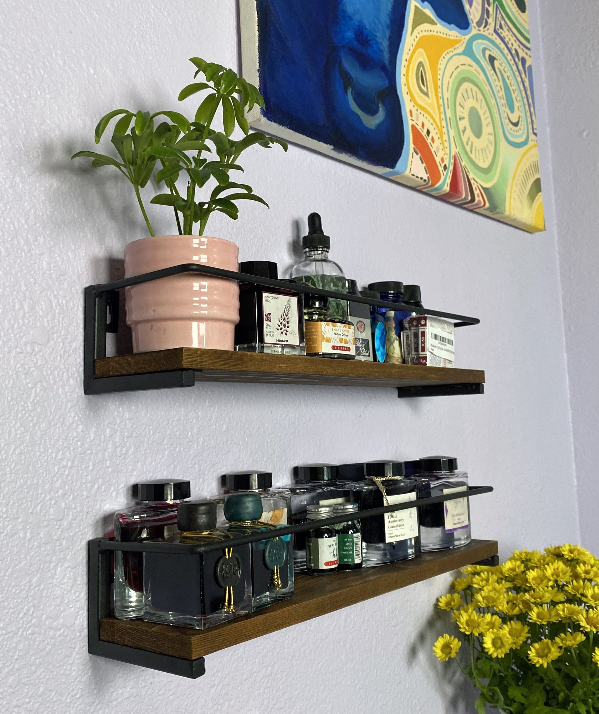 A left side view of the 2 spice racks being used to hold ink bottles and a potted plant.