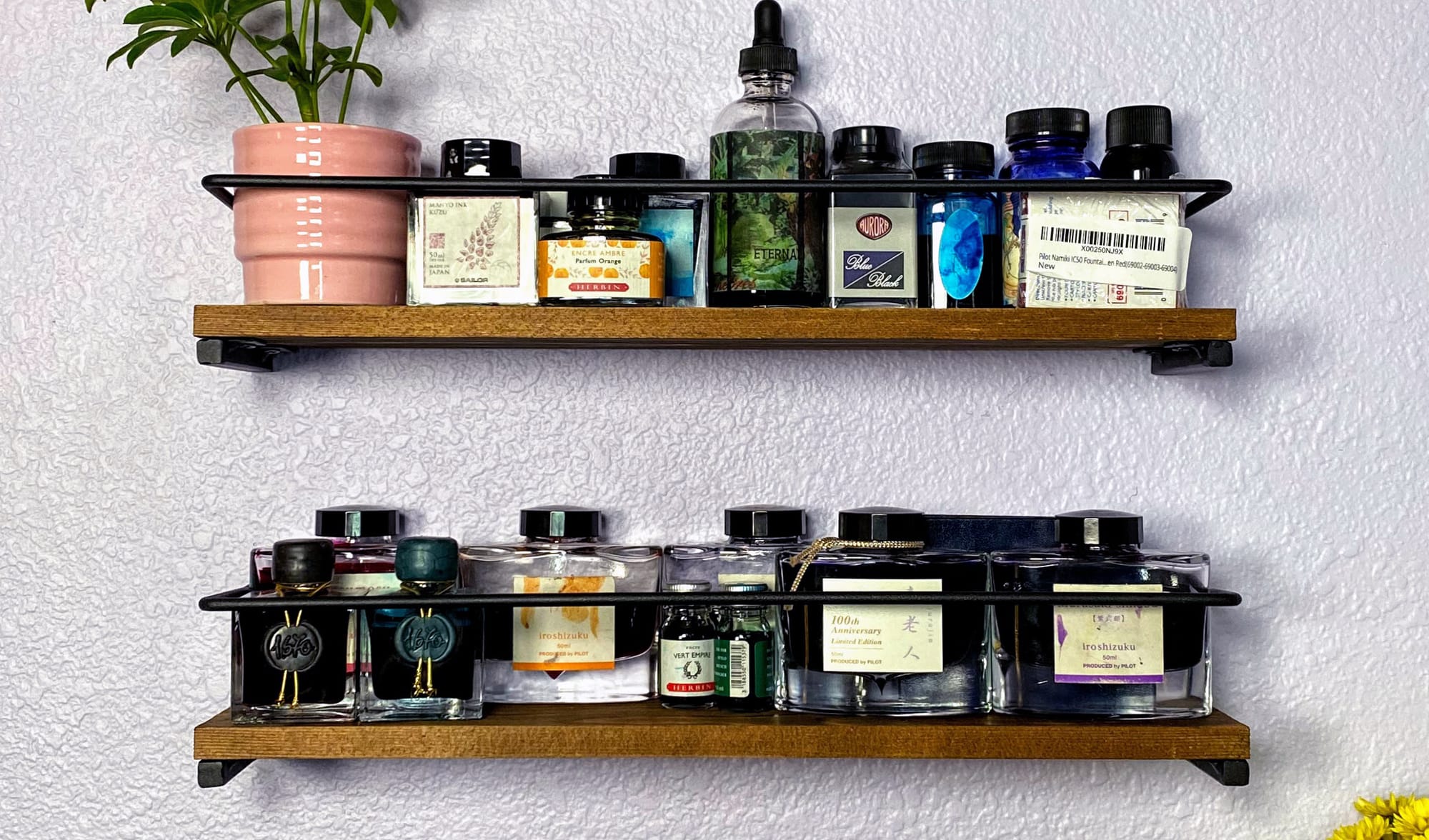 Spice racks on a wall holding multiple ink bottles and a potted plant.