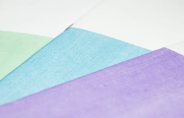 Zoomed in photo of green, blue, and purple painted notebooks stacked and splayed out.